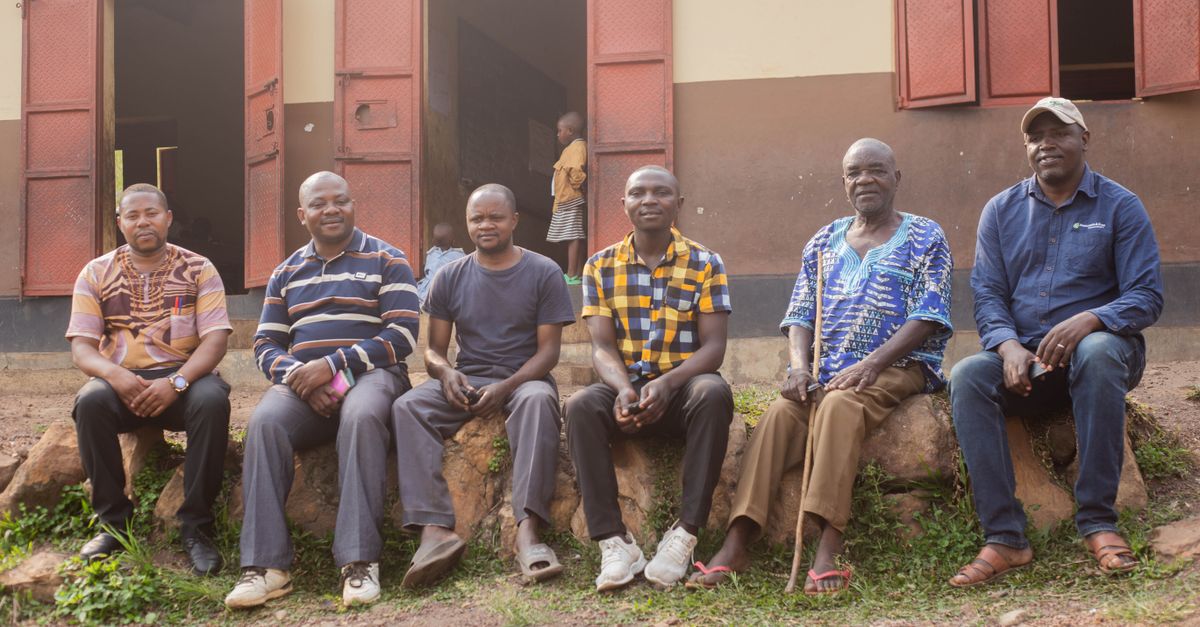 A group of community members gathered outside a church in rural Volta Region, with health workers setting up screening equipment