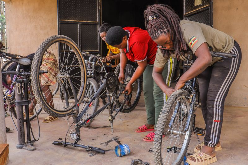 Three women collaboratively repairing bicycles in an indoor workshop.
