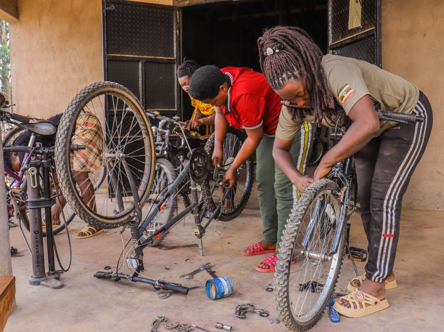 Two bicycle mechanics in aprons at the workshop doorway