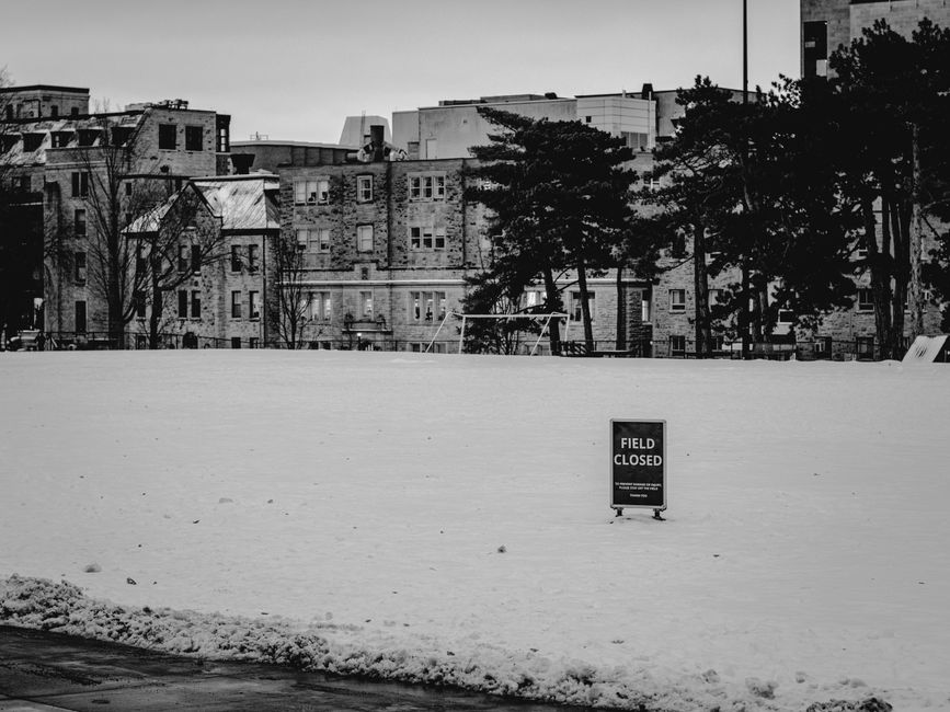 Black and white image of a snow-covered field with a 'FIELD CLOSED' sign in Kingston, Ontario.