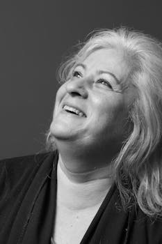 Black and white portrait capturing the joyful expression of a senior woman looking upwards.