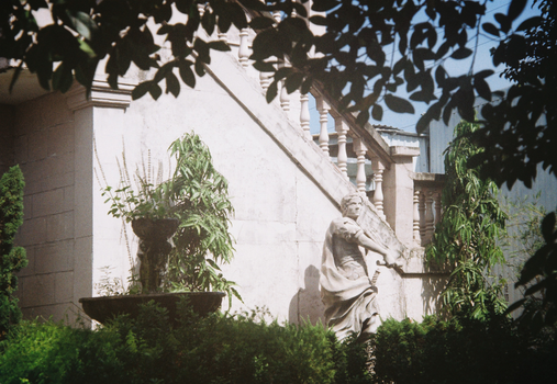 Classical garden scene with a stone statue and lush greenery for serene ambiance.