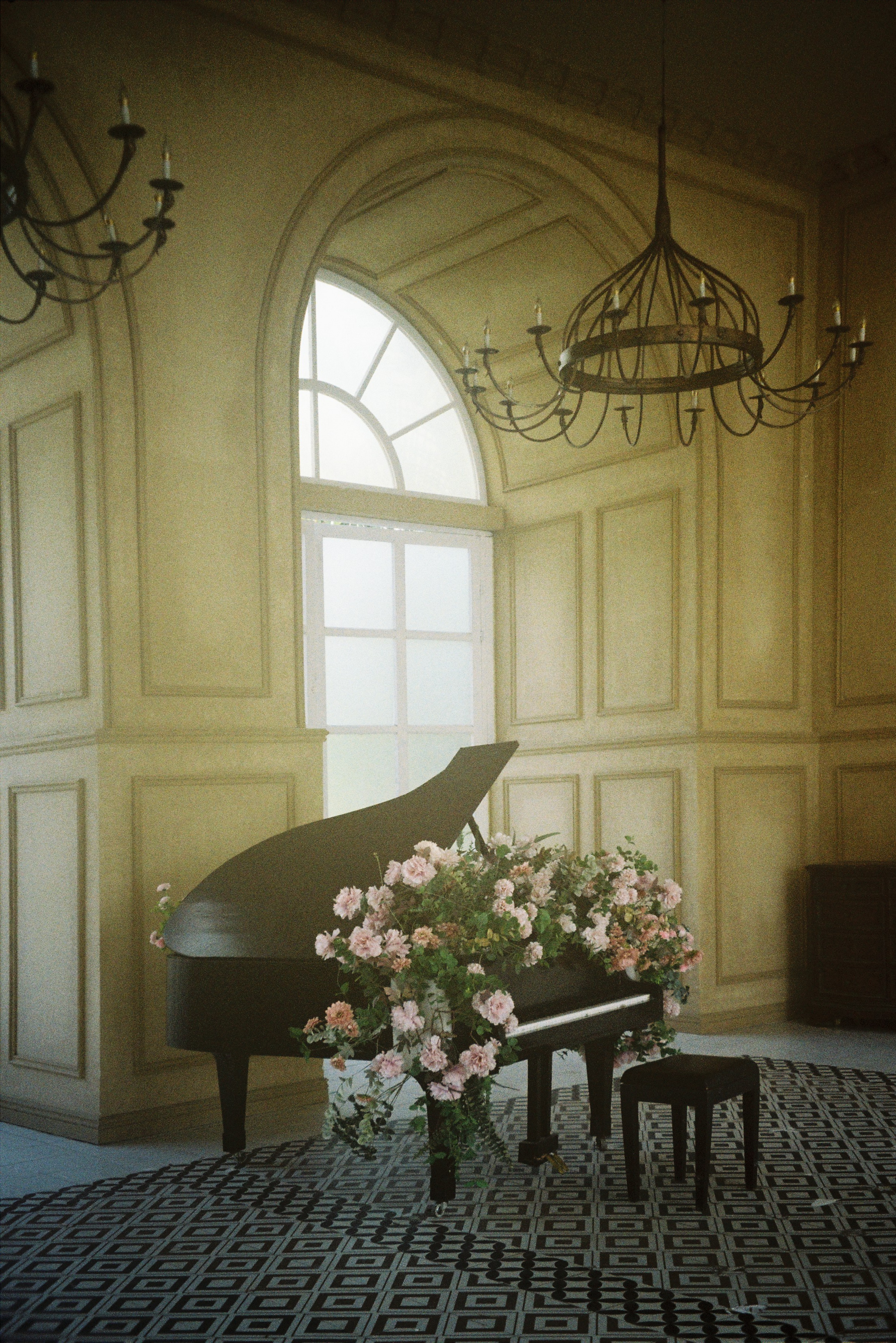A grand piano adorned with blossoms in an elegant vintage styled room.