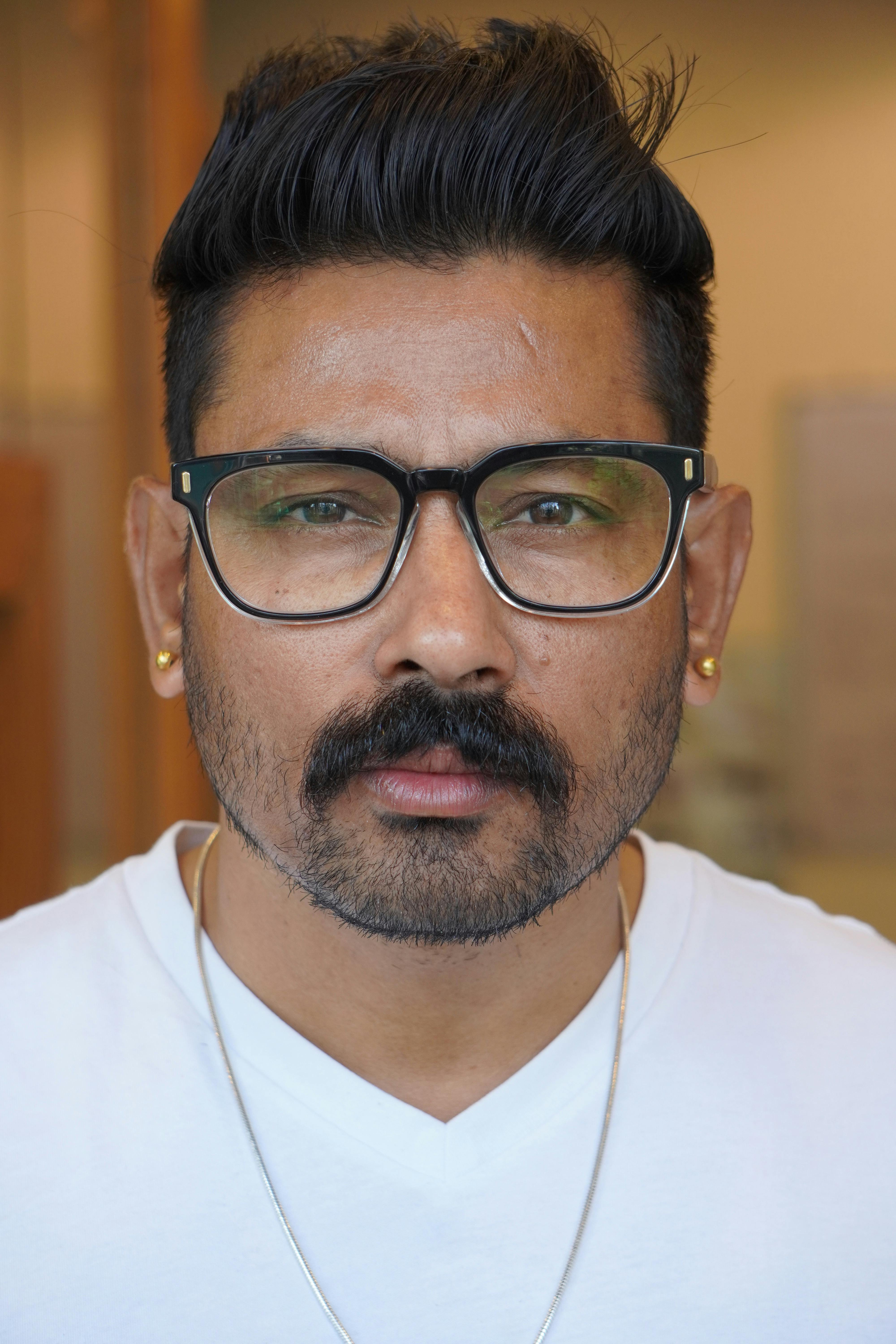 A detailed close-up portrait of a man with glasses and a mustache.