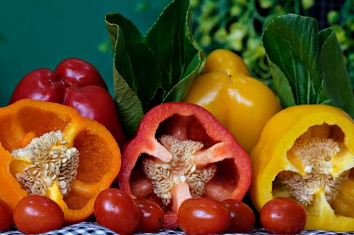 Free Colorful arrangement of bell peppers and cherry tomatoes with fresh greens. Stock Photo
