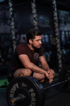 Focused athlete rests between sets in the gym, showcasing strength and determination.