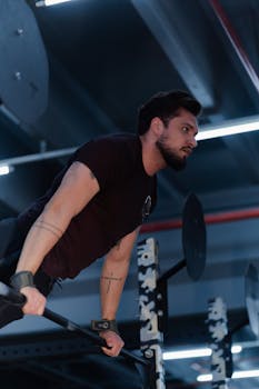 Man in a gym executing an intense horizontal bar routine showcasing strength and focus.
