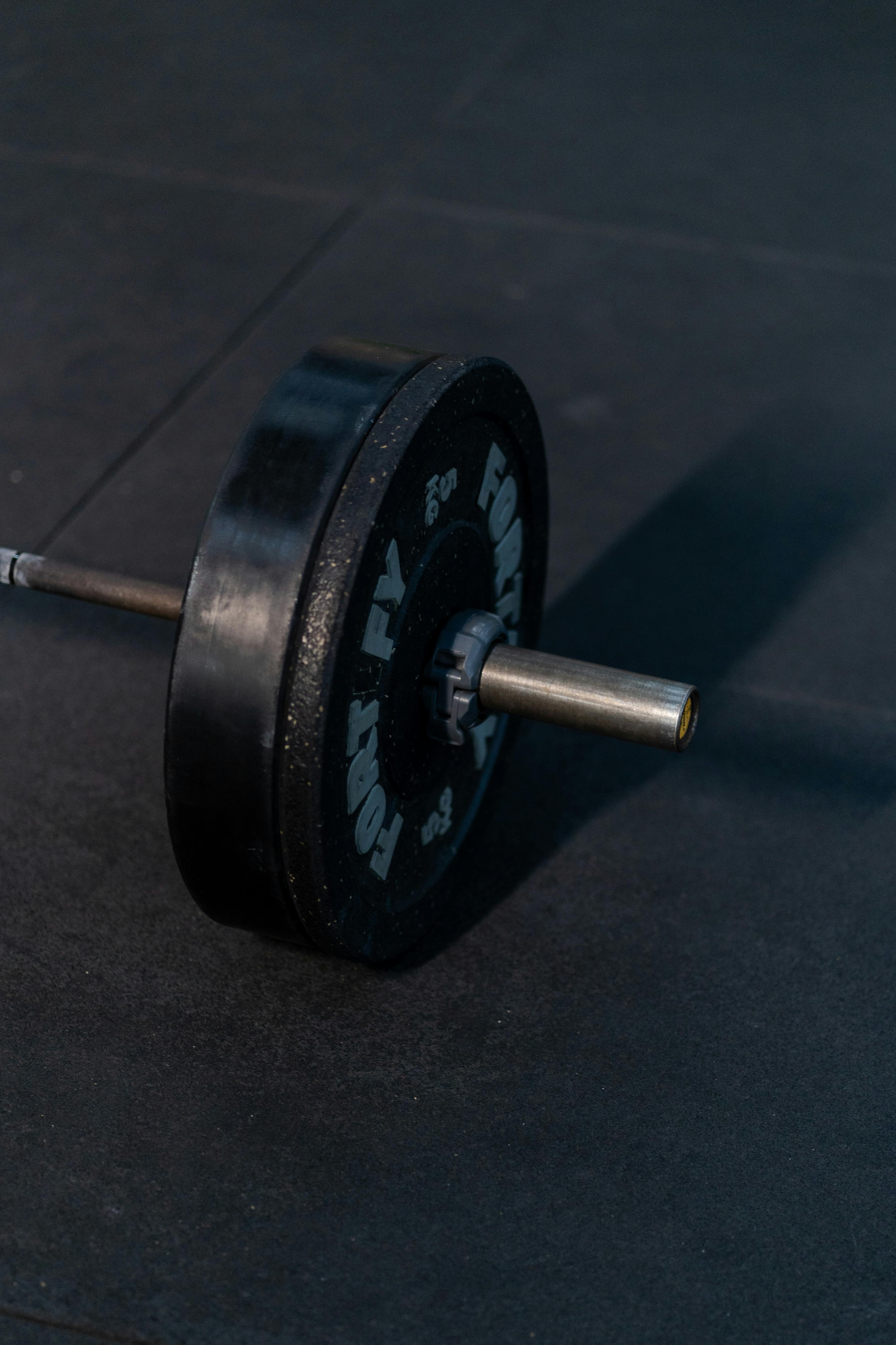 High-quality image of a barbell with weights on a gym floor, ideal for fitness themes.