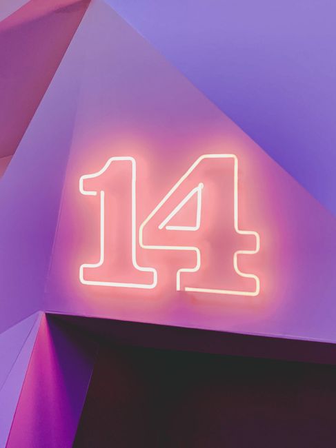 Glowing neon number 14 on a colorful geometric background, perfect for modern design projects.