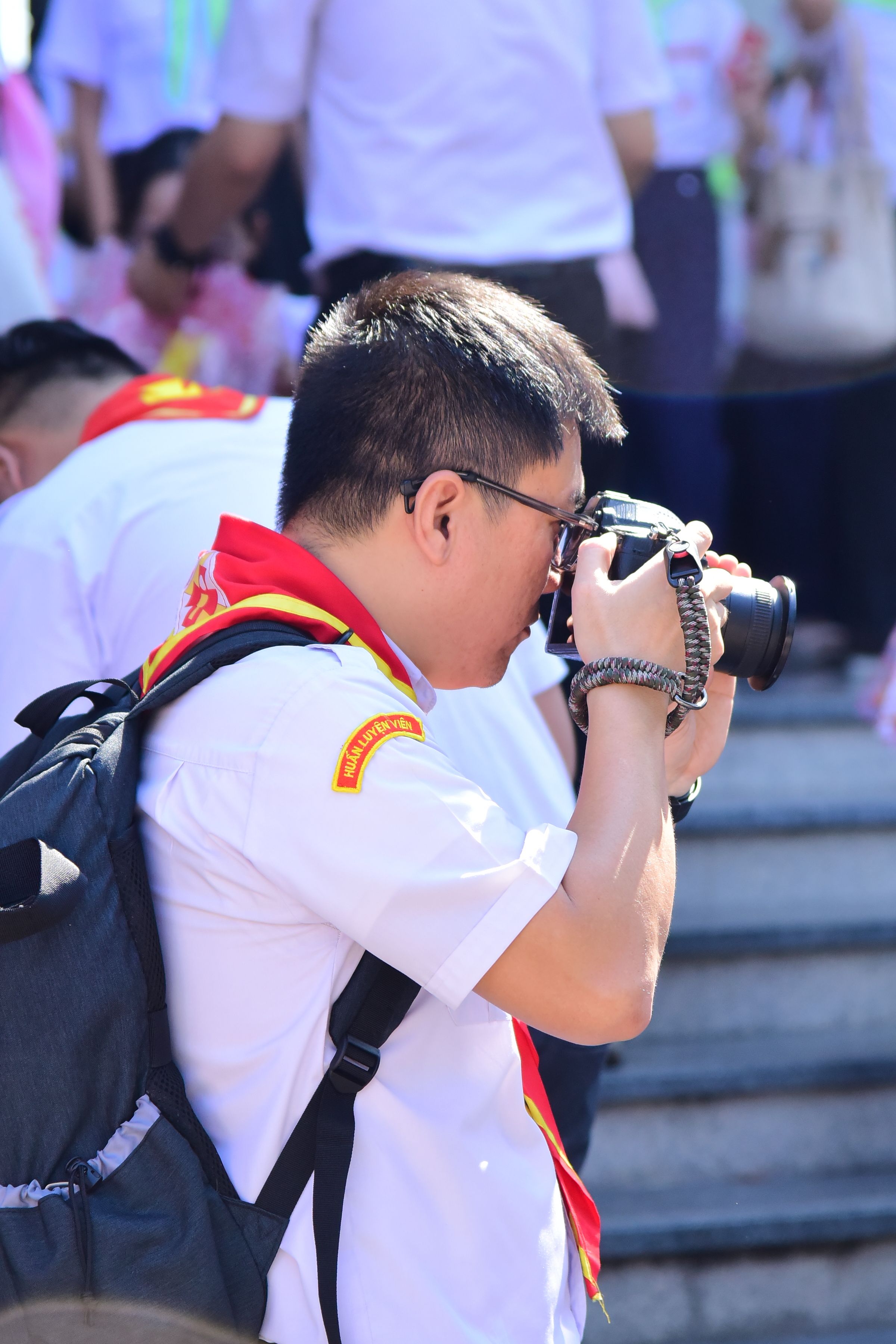 A man with a DSLR camera captures moments at a crowded outdoor event.