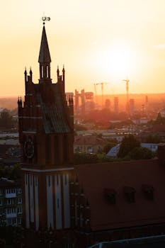 Stunning Gothic church silhouette with a vibrant sunrise backdrop over a cityscape.
