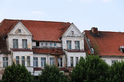 Free Aged building with red tiled roofs showcasing classic European architecture amid lush greenery. Stock Photo