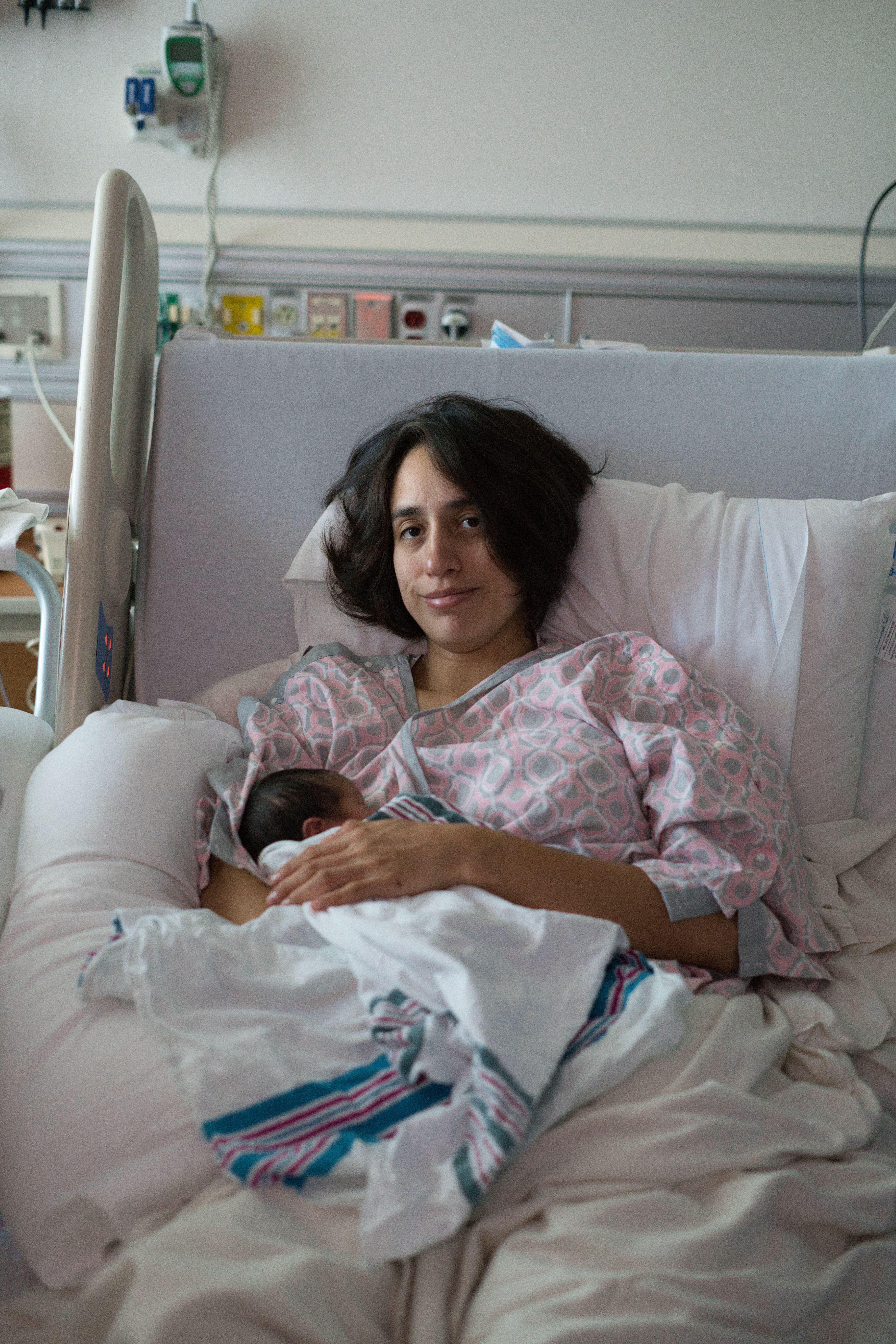 A new mother lovingly holds her newborn in a hospital setting post-delivery.