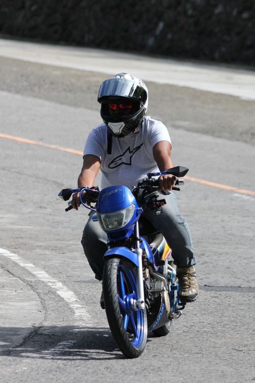 Free Person with helmet riding a blue motorcycle on a city street, focusing on safety and travel. Stock Photo