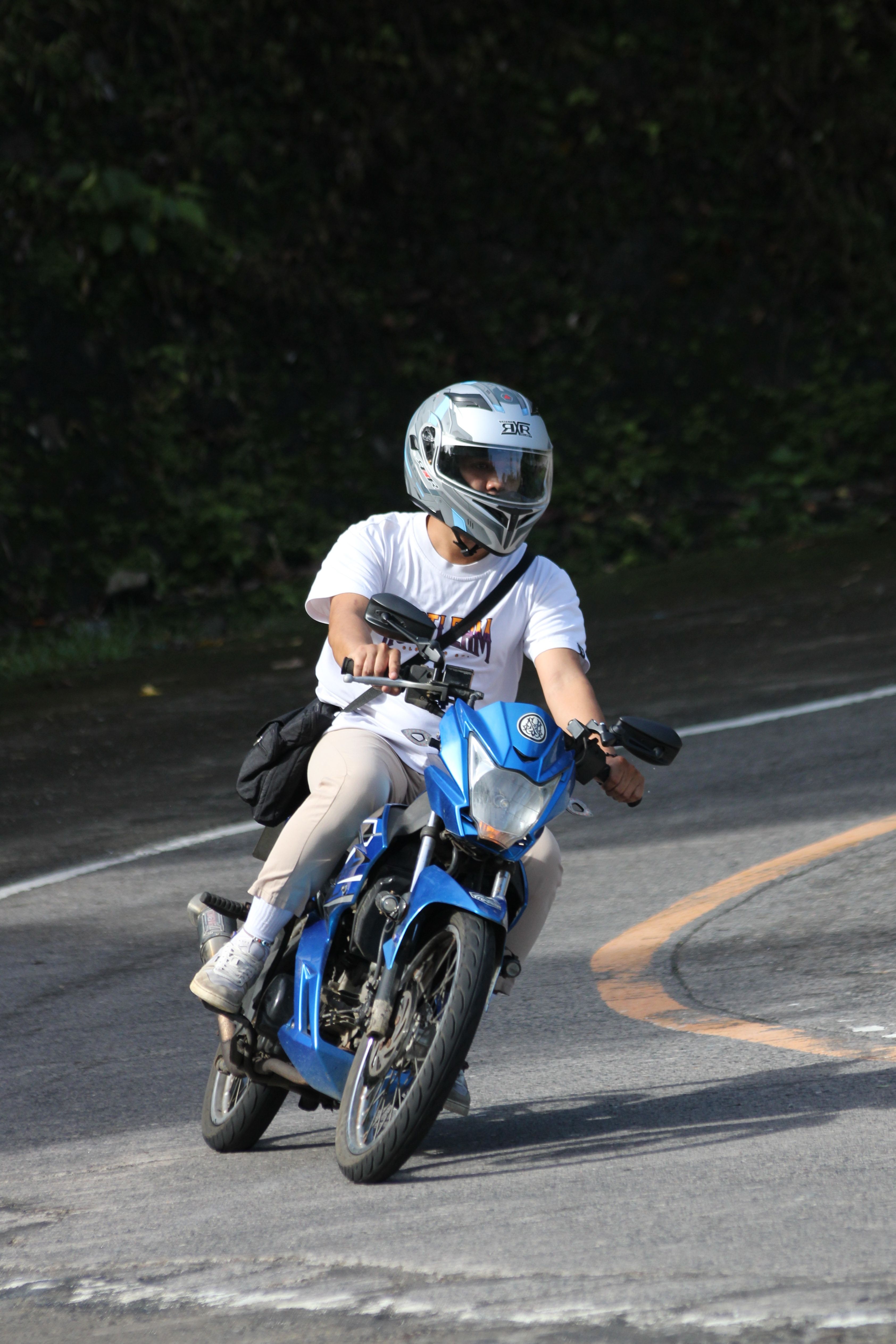 Motorcyclist Riding Blue Bike on Curved Road · Free Stock Photo