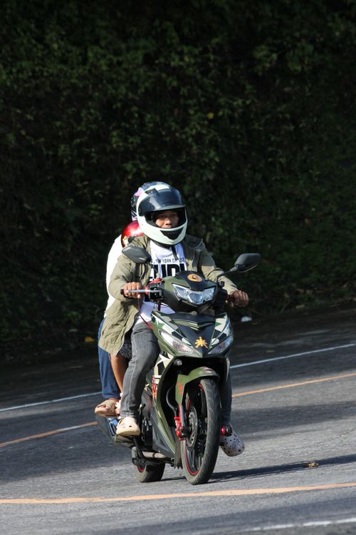 Free Two people on a motorcycle navigate a winding road surrounded by greenery. Stock Photo