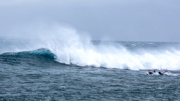 Surfers approaching powerful ocean waves, capturing the thrill of surfing adventure.