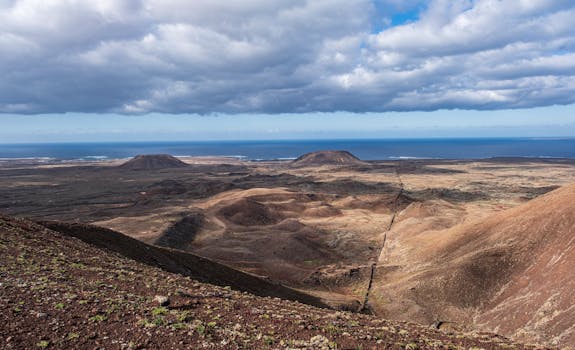 A breathtaking view of volcanic terrain in Corralejo, Canary Islands under dramatic clouds.