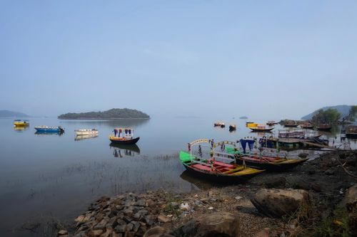 Free Colorful boats floating on Maithon Lake, Jharkhand, India, surrounded by serene waters and lush islands. Stock Photo