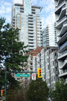 View of Pacific Street in Vancouver, showcasing modern high-rise buildings with a traffic light and greenery.