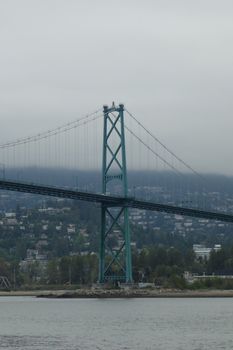 Lions Gate Bridge spanning Burrard Inlet with cloudy backdrop in Vancouver, BC, Canada.