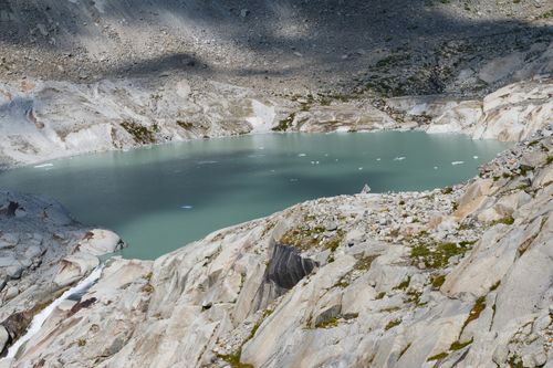 Free A breathtaking view of a serene alpine lake surrounded by rocky terrain in Switzerland. Stock Photo