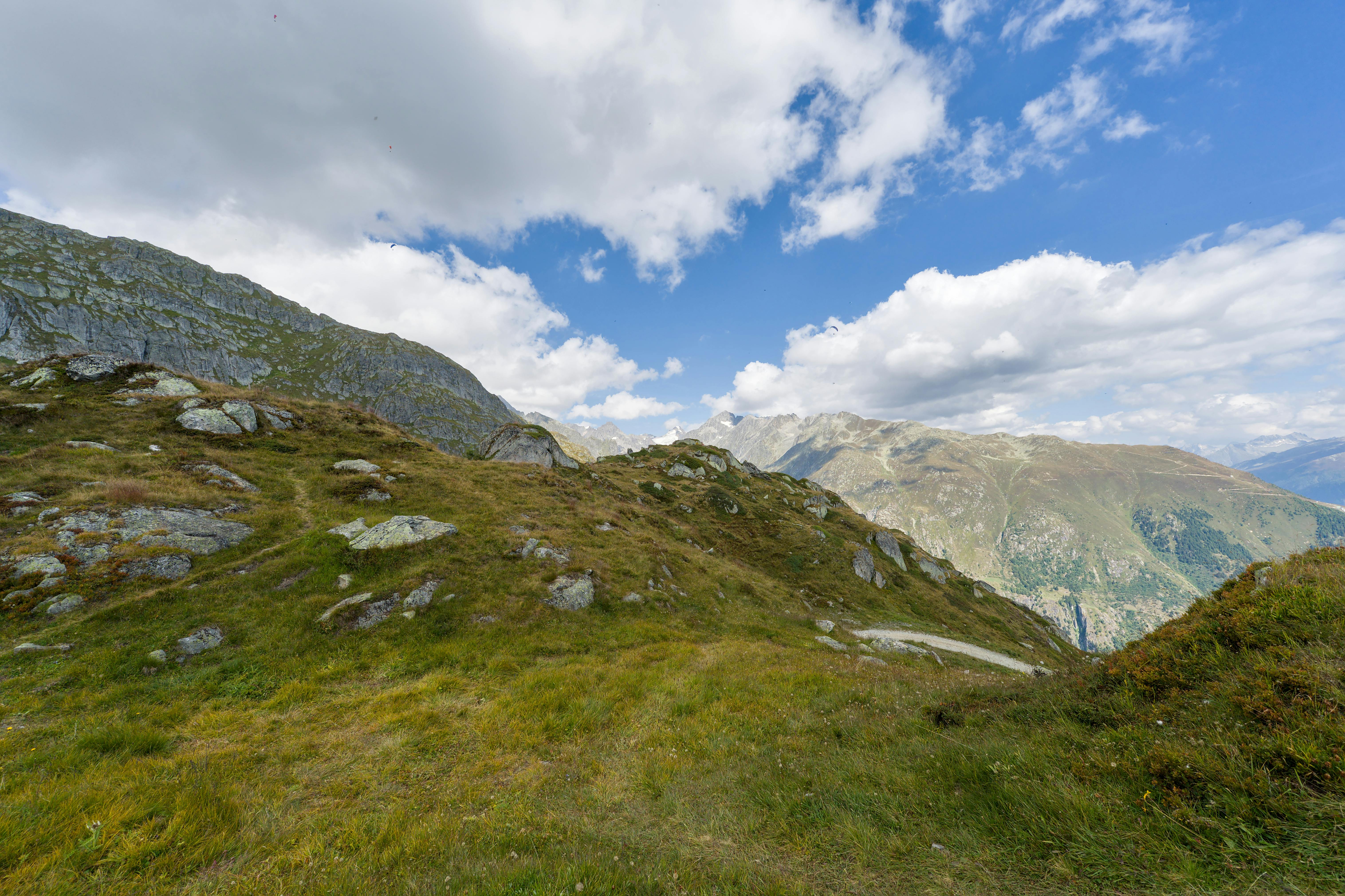 Breathtaking view of the Swiss Alps with lush green hills and a clear blue sky.