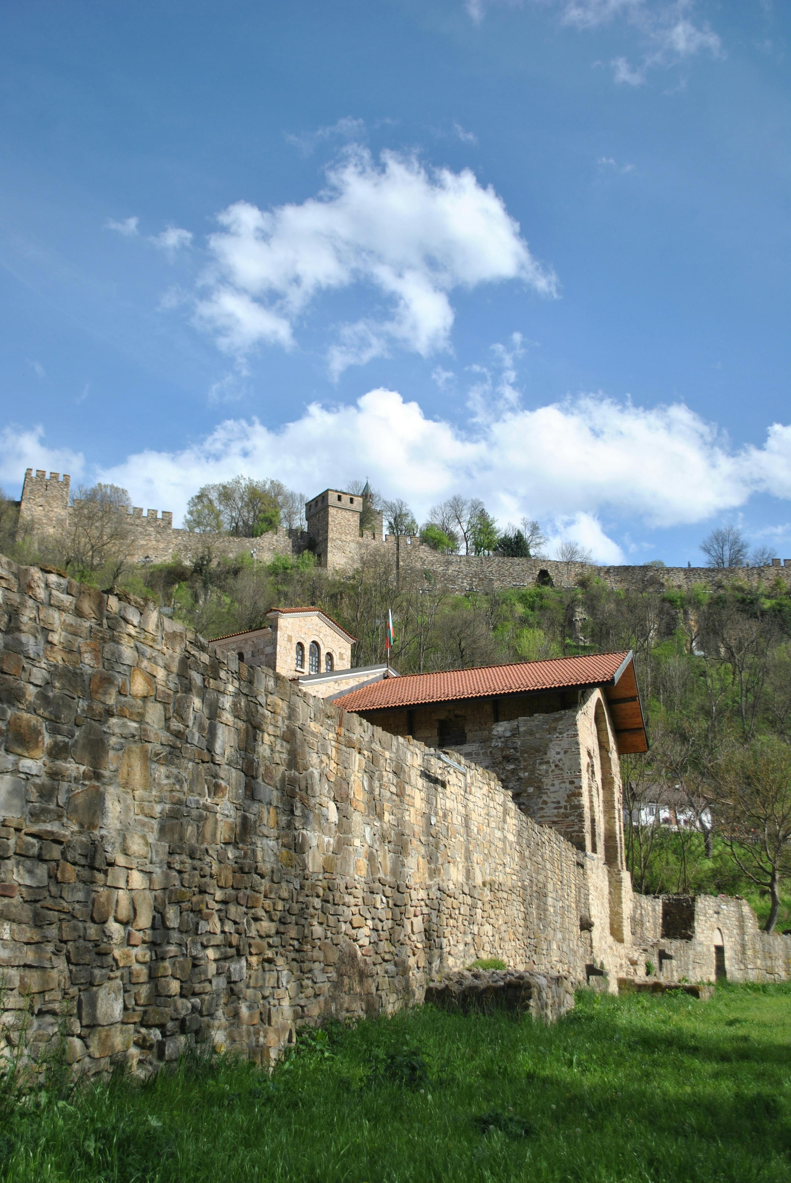 Historic stone fortification with lush greenery and blue sky, perfect for travel or history themes.