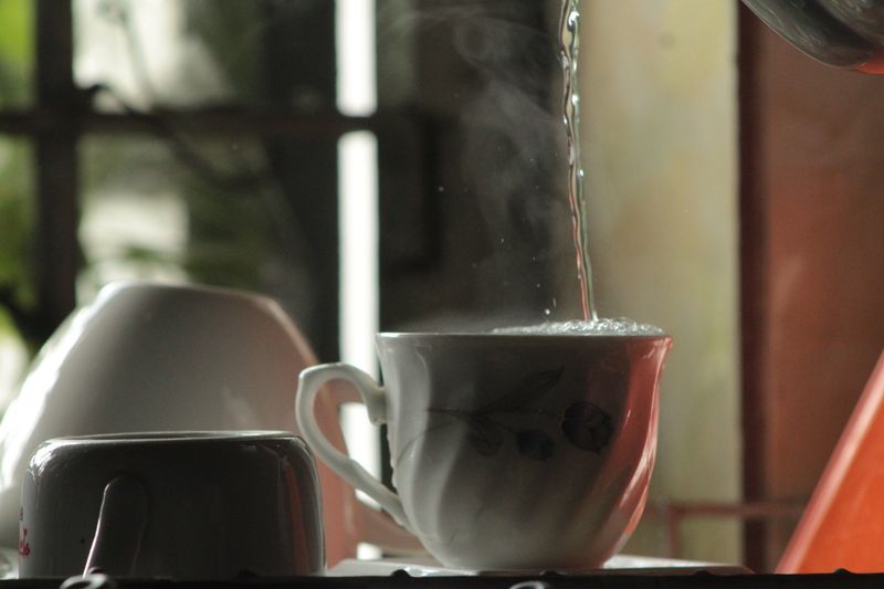 Hot water being poured into a teacup for steeping green tea