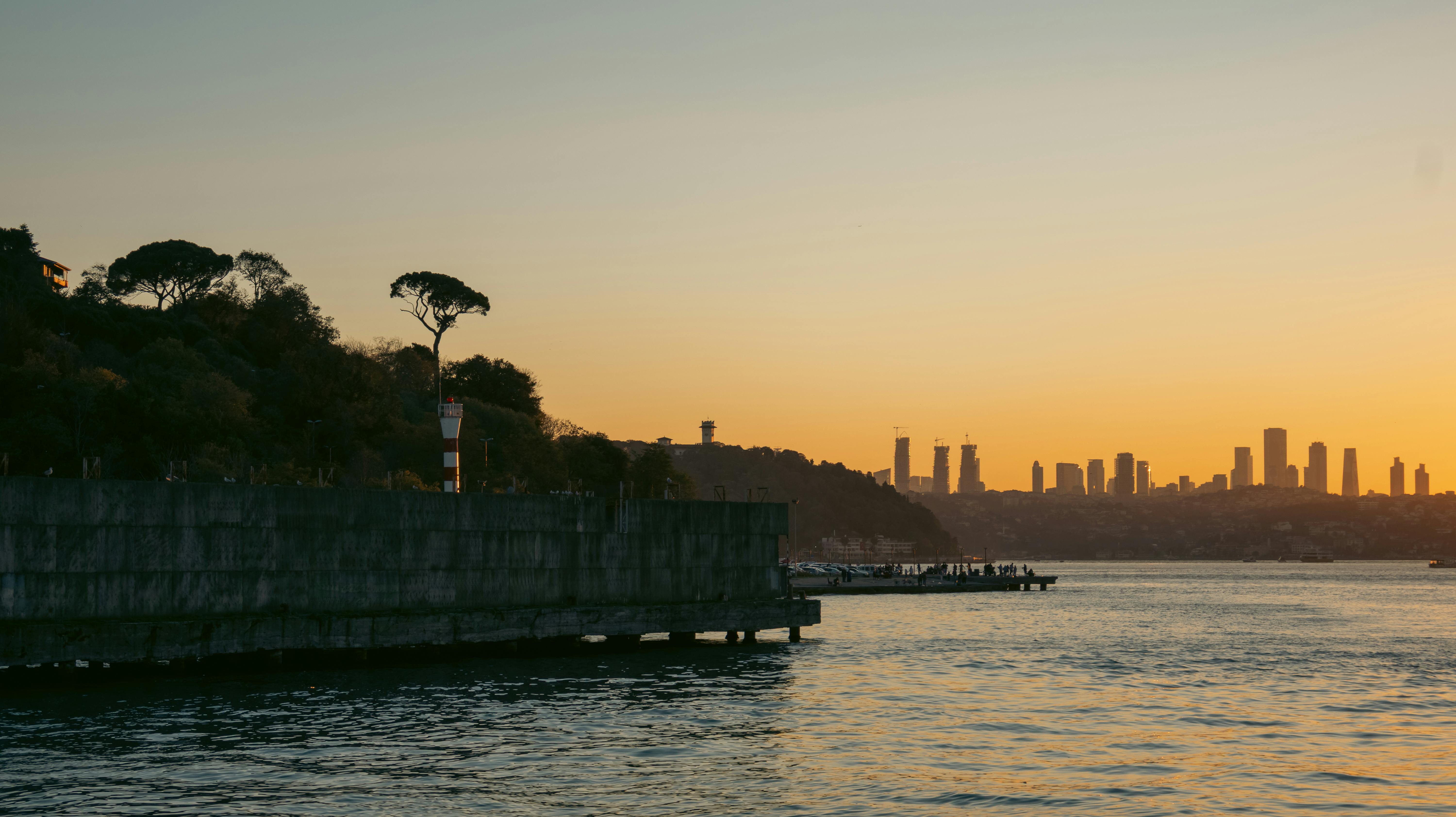 夕阳西下，城市天际线在平静的水面上映衬，呈现出温暖的色调，景色迷人。