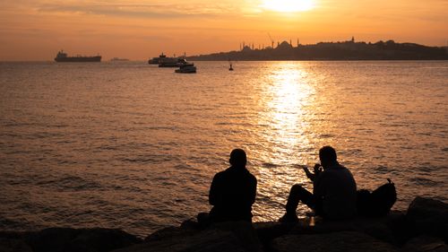 Free Two silhouettes enjoy a stunning sunset over the Bosphorus in Istanbul. Stock Photo