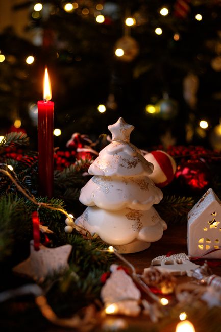 A cozy holiday setup featuring a red candle, ornaments, and festive decorations.