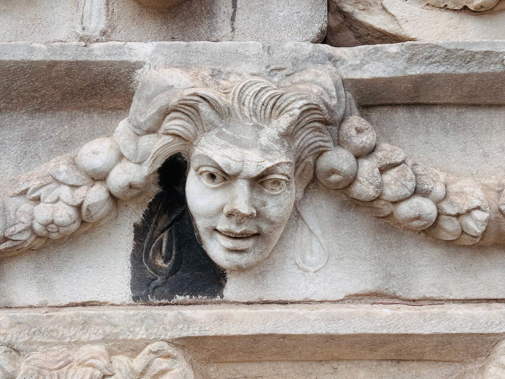 Detailed view of a classic Medusa face carving on ancient stone architecture.
