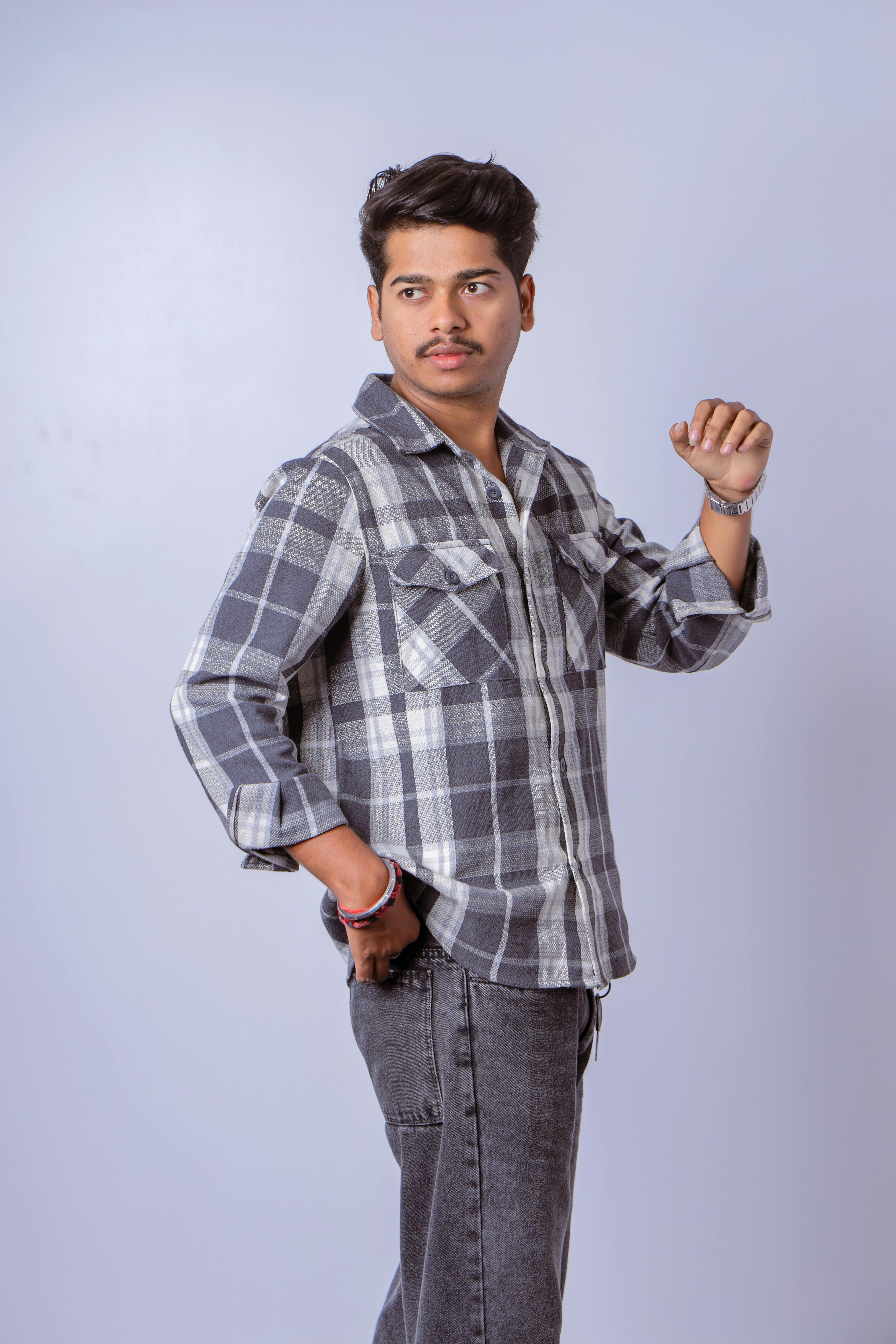 grátis Retrato de um jovem estiloso posando com uma camisa xadrez e calça jeans. Foto profissional