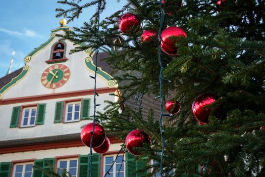 Festive Christmas tree with red ornaments in front of historic Weil der Stadt building.