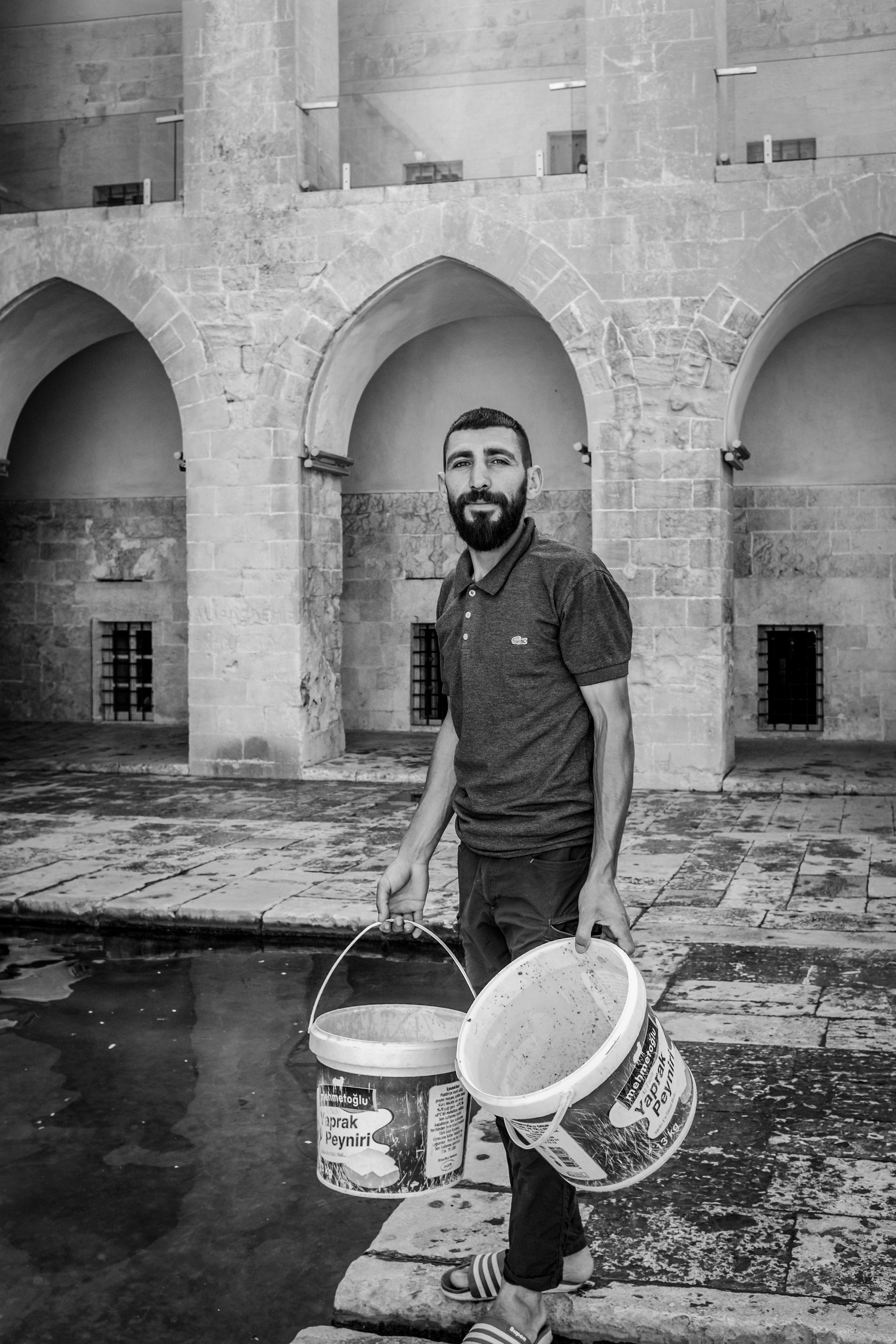 Man Carrying Buckets in Historic Courtyard · Free Stock Photo