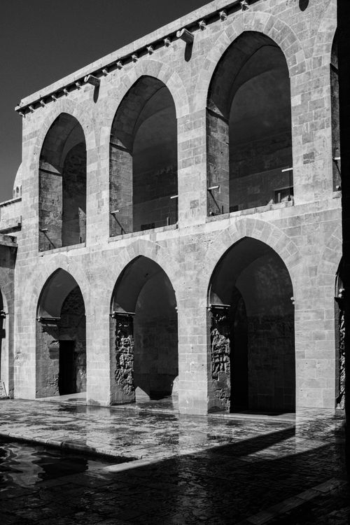 Free Monochrome image of historic stone arches in a courtyard. Perfect for classic architecture themes. Stock Photo