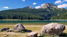 蔚蓝的天空下，山湖景色秀丽，针叶林与岩石相映成趣