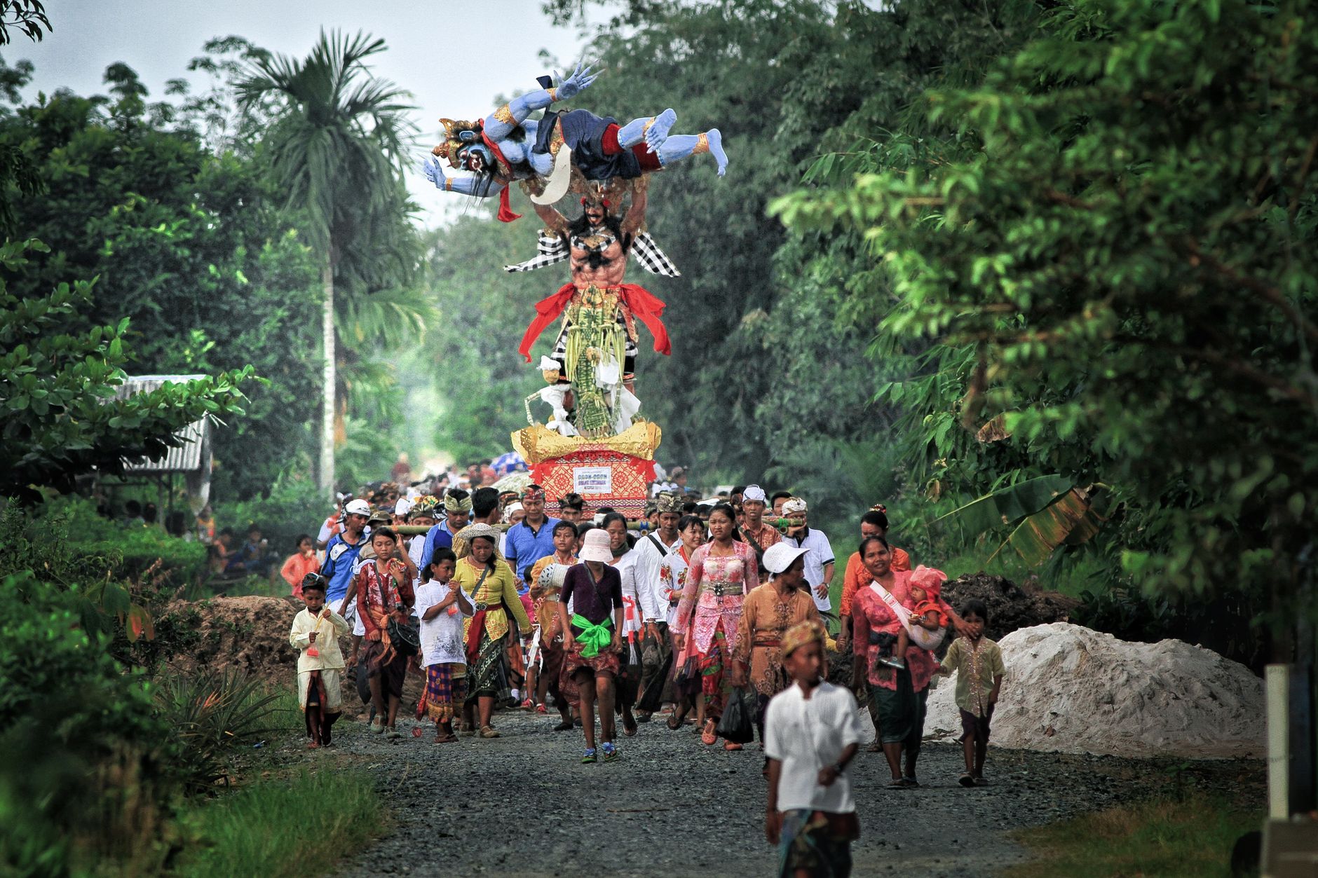 Colorful Ogoh-Ogoh festival procession in the lush greenery of Kalimantan Selatan, Indonesia.