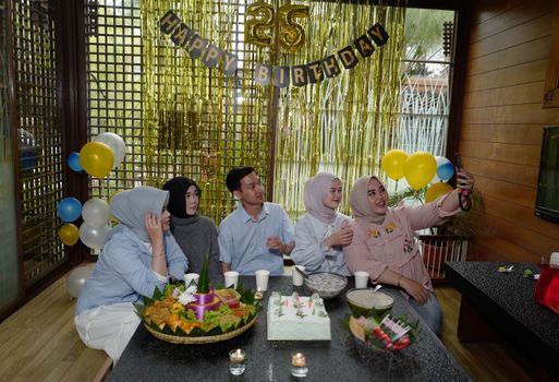 Five friends celebrating a 25th birthday indoors in Indonesia, capturing memories. - Fotografer Sidoarjo
