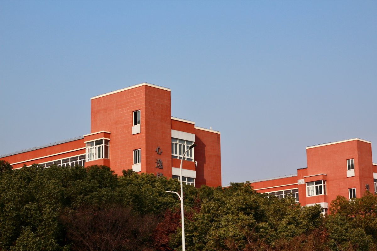 Red brick educational building surrounded by greenery