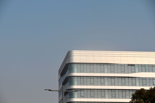 A modern office building with glass windows against a clear blue sky, showcasing architectural design.