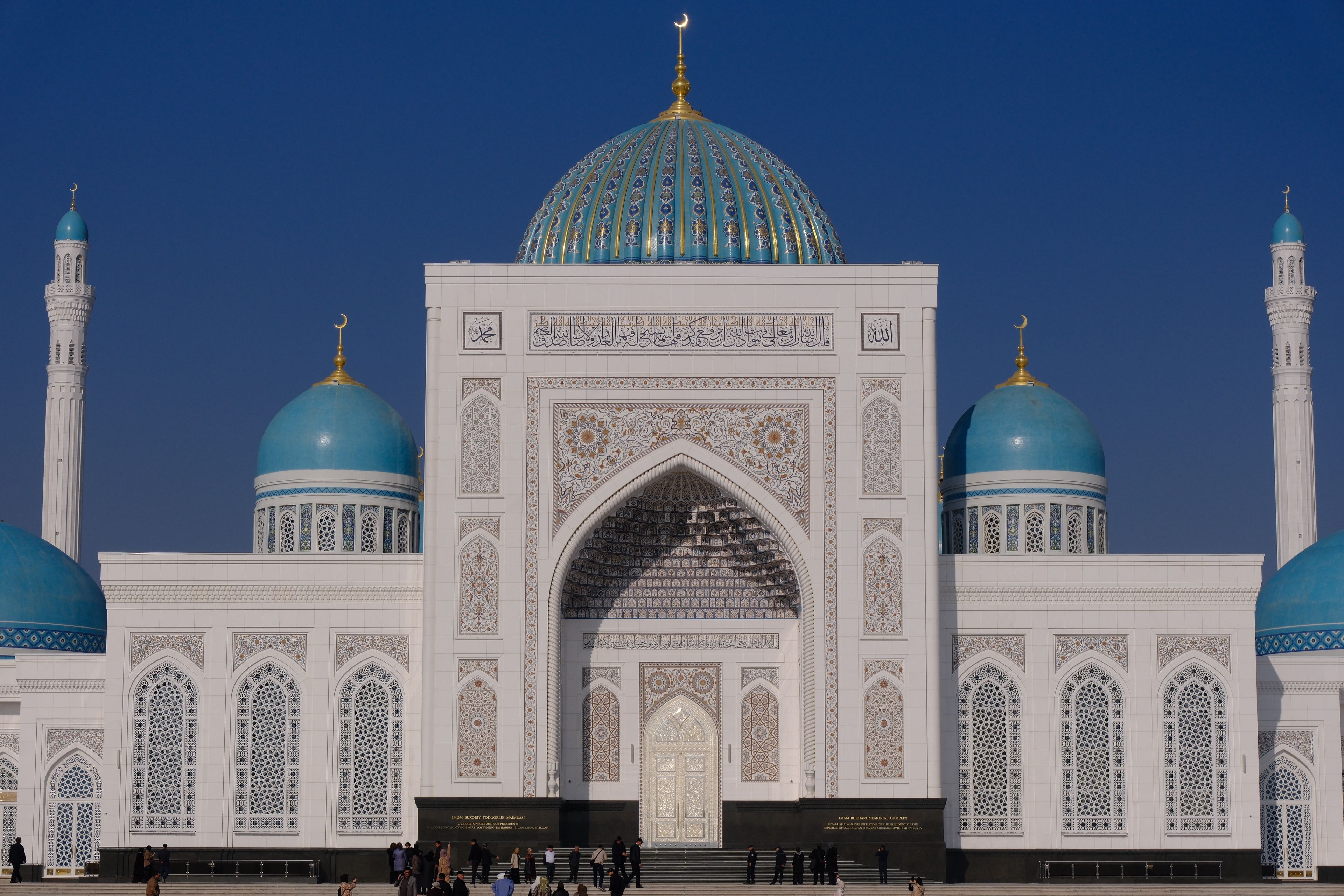Stunning view of a grand mosque with blue domes under a clear sky.