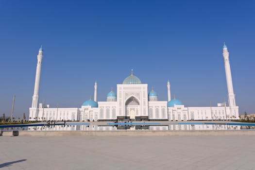 Beautiful Hazrat Sultan Mosque under a clear blue sky, reflecting in the courtyard