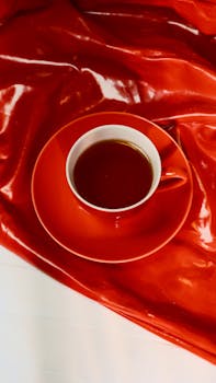 Capture of a vibrant red tea cup on glossy red satin fabric. Perfect for lifestyle or food themes.