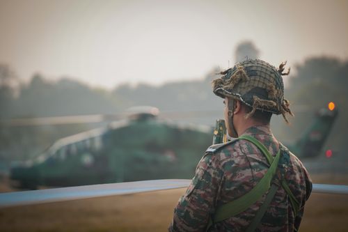 Free A soldier in camouflage stands with a helicopter in the background, Kolkata, India. Stock Photo