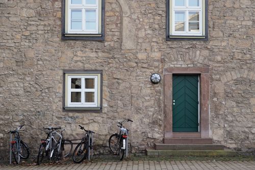 Free A quaint stone facade with a green door and bicycles parked outside in Göttingen, Germany. Stock Photo