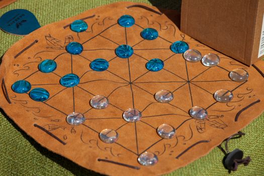 Colorful glass pieces on a leather board game mat, offering a historical or strategy theme.