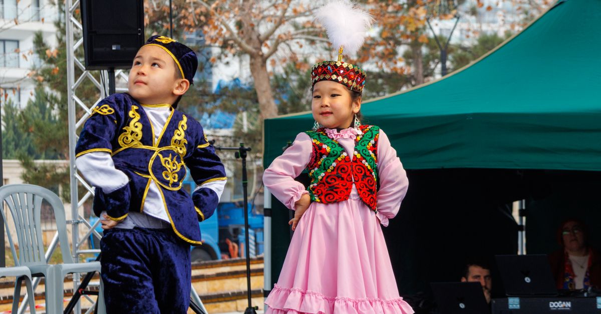Two children in colorful traditional attire performing outdoors during daytime.