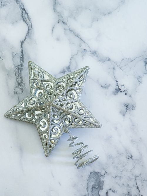 Free Elegant silver star tree topper on marble surface, perfect for festive decorations. Stock Photo